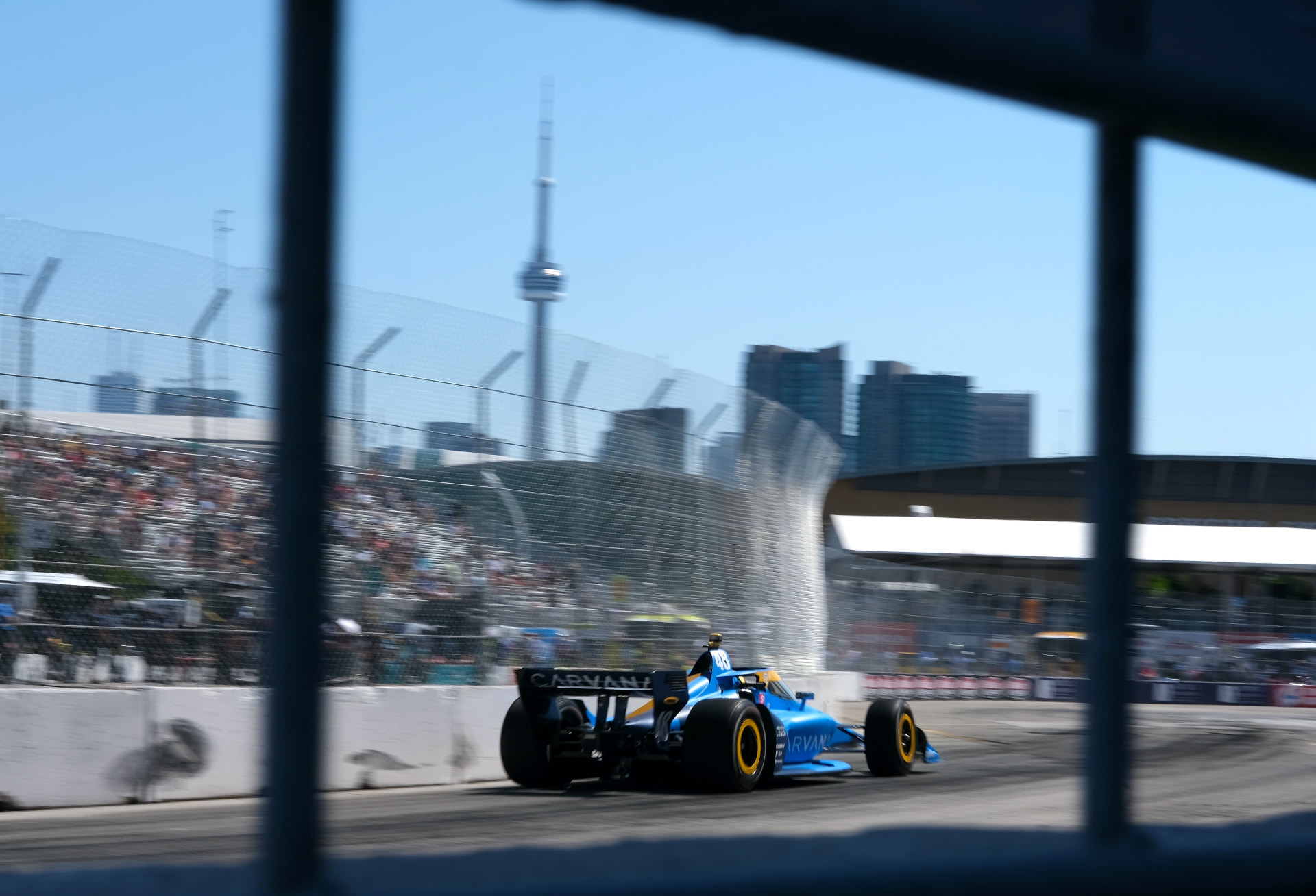 Carvana IndyCar through the fence with the CN Tower behind